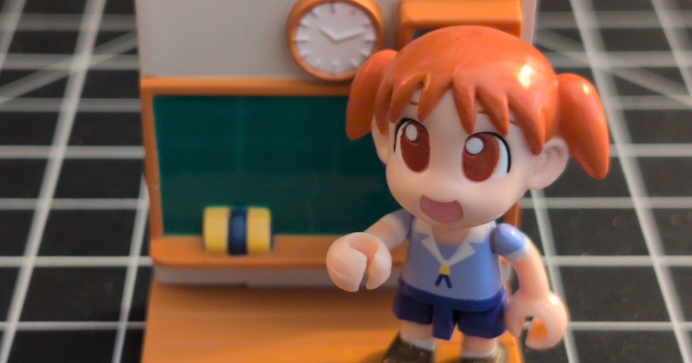A Chiyo toy from Azumanga Daioh standing at the front of a classroom.